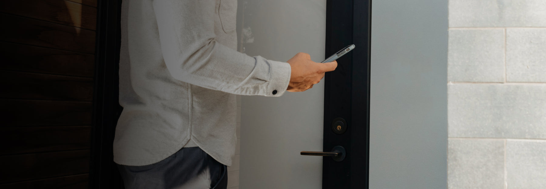 A man opening his front door through he August smartphone app