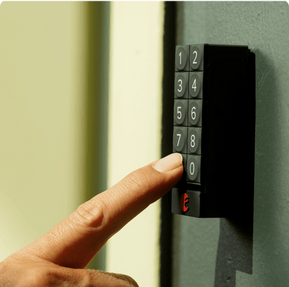 A persons finger pushes a button on a black August Home keypad door lock